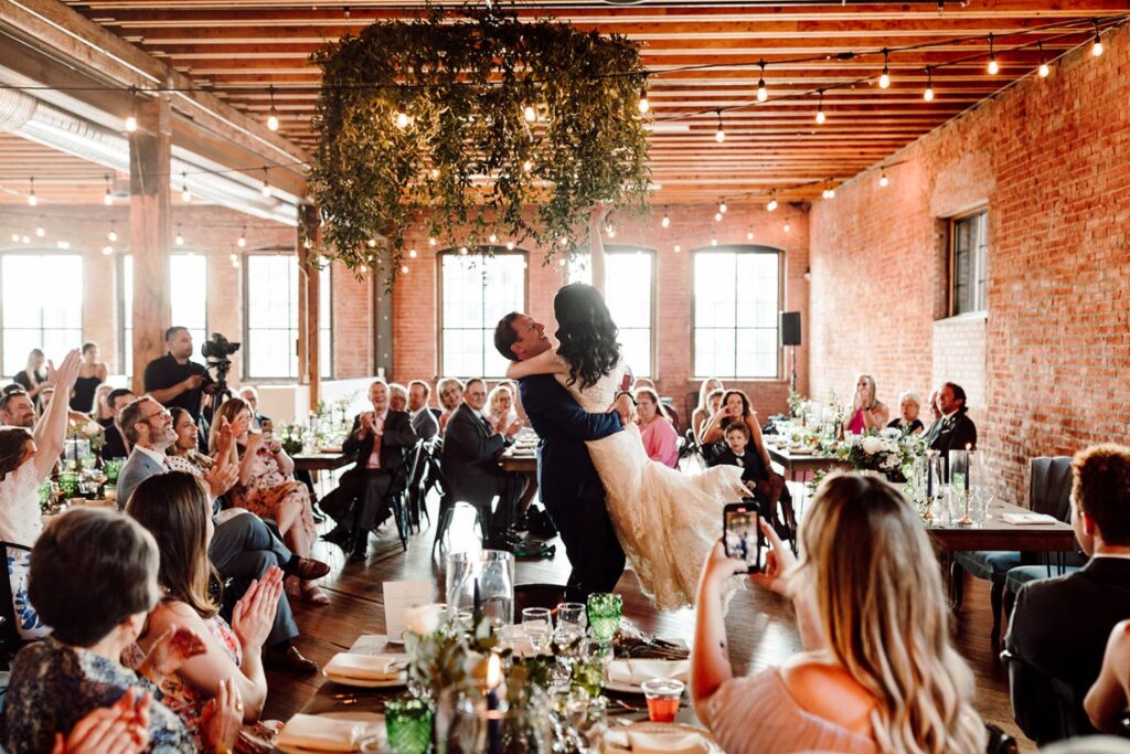 Bride and groom's first dance at a wedding reception at UNION in Kansas City, MO, with guests watching and warm string lights overhead.