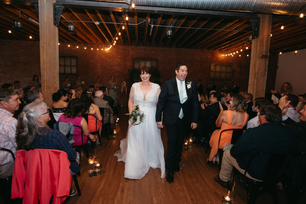 A bride and groom walking down the aisle after just getting married at UNION in Kansas City, Missouri.