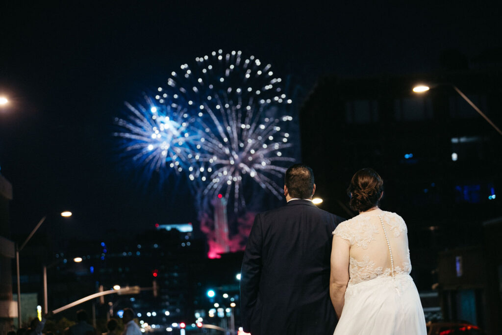 A bride and groom watching a fireworks show from the rooftop at UNION in Downtown Kansas City, Missouri.