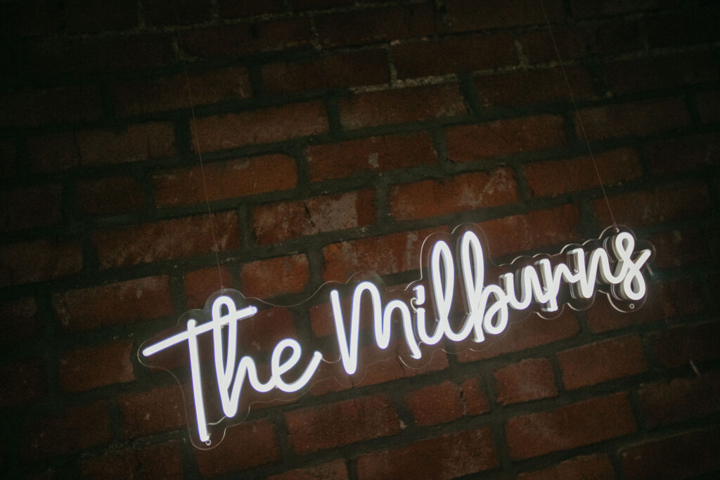 Neon sign on a brick wall reading "The Milburns"