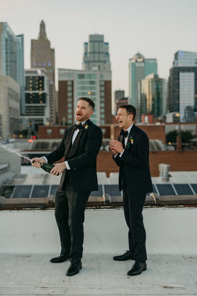 Two grooms popping champagne on UNION's rooftop in Kansas City