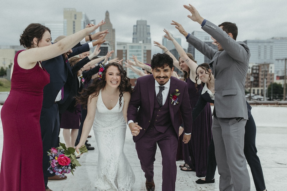 Bride and Groom run through a group of people holding their arms up in Kansas City for a wedding.