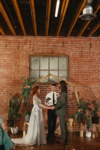 Bride and groom standing in front of a wooden hexagon arch and lots of plants for their wedding ceremony at UNION in downtown Kansas City.