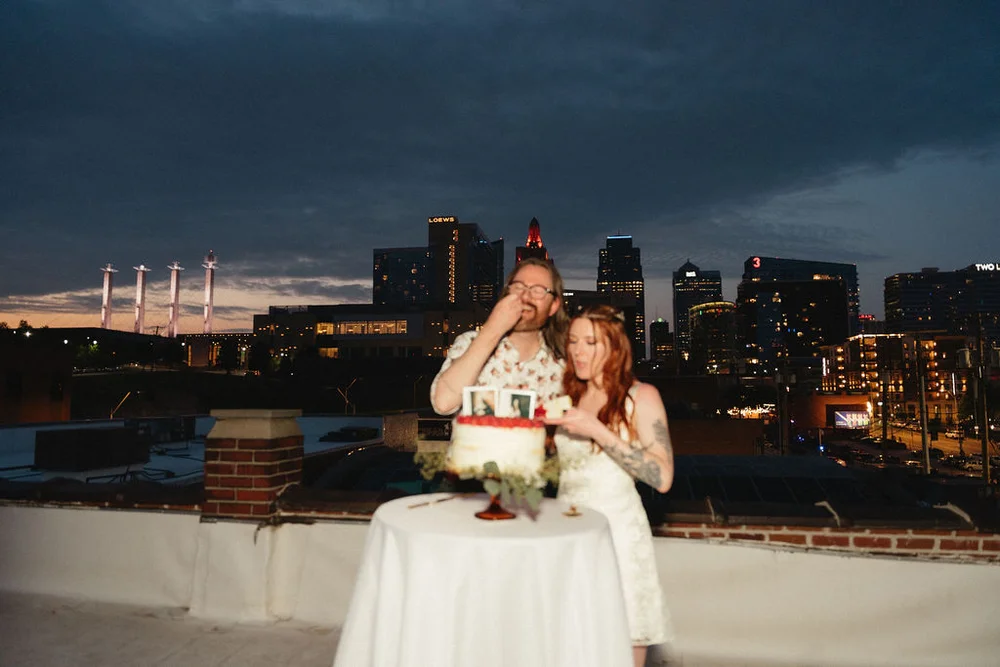 Bride and groom cutting their single-tiered wedding cake with their photos as the topper, on UNION's rooftop overlooking downtown Kansas City.