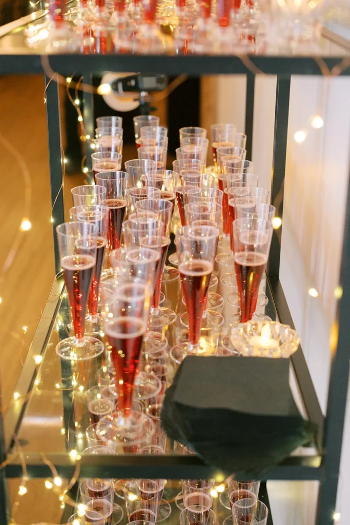 Shelving display holding champagne classes full of a red cocktail at kansas city office holiday party.