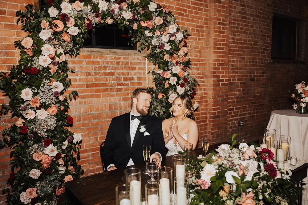 Bride and groom at sweetheart table with florals and candles at UNION Kansas City wedding