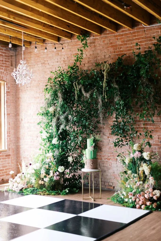 Black and white dance floor with hanging greenery and green wedding cake at UNION Kansas City
