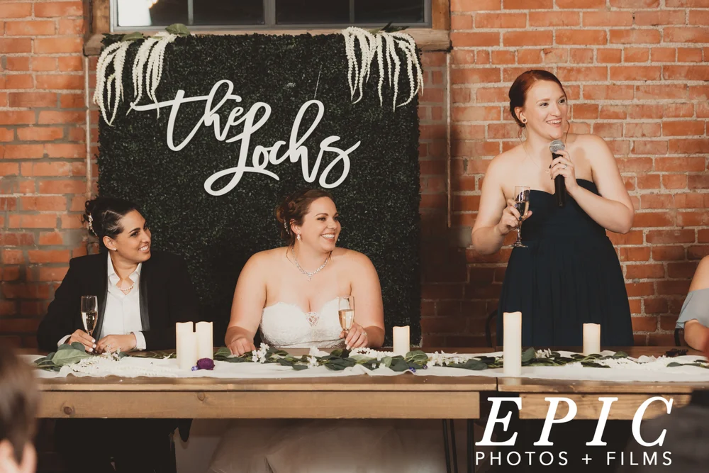 Two brides sitting at their sweetheart table during speeches at UNION in Kansas City MO